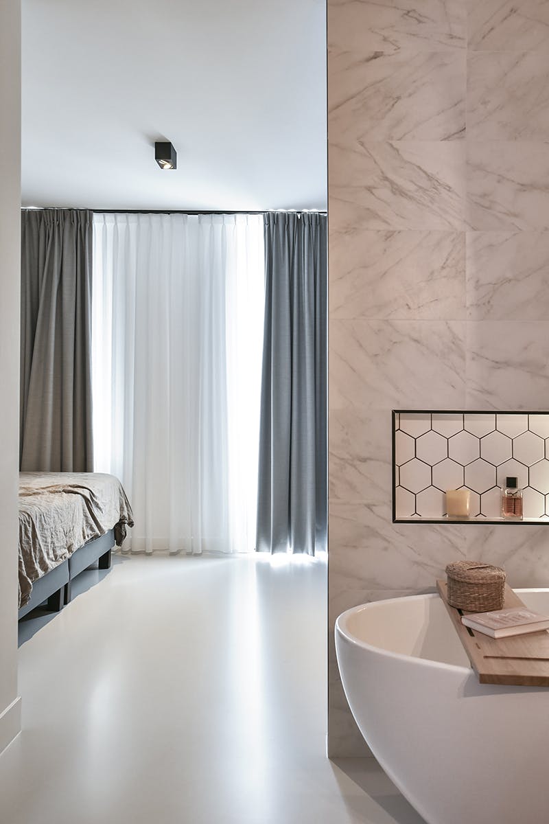 Slaapkamer met gordijnen en aansluitende badkamer